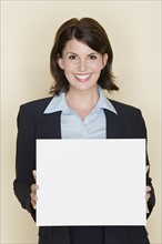 Portrait of smiling businesswoman holding blank page, studio shot. Photo : Rob Lewine