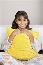 Portrait of smiling girl (10-11) in bed with pillow. Photo: Rob Lewine