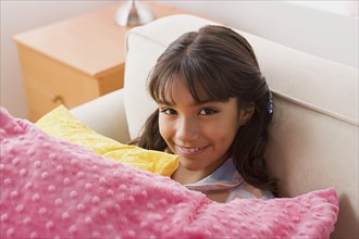 Portrait of smiling girl (10-11) with pillows. Photo : Rob Lewine