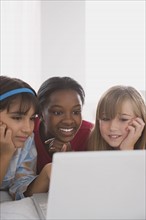 Portrait of three girls (10-11) using laptop. Photo : Rob Lewine