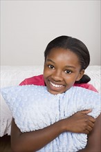Portrait of smiling girl (10-11) with pillow. Photo : Rob Lewine