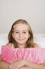Portrait of smiling girl (10-11) with pillow. Photo: Rob Lewine