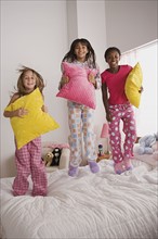 Portrait of three girls (10-11) jumping on bed at slumber party. Photo : Rob Lewine