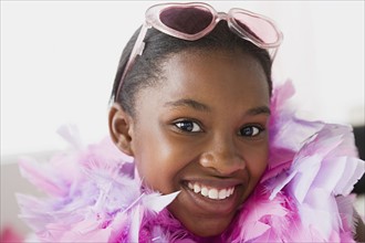 Portrait of smiling girl (10-11) wearing feather boa and sunglasses. Photo : Rob Lewine