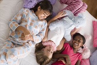 Three girls (10-11) lying on bed at slumber party. Photo: Rob Lewine