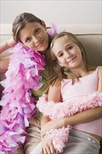 Portrait of mother and daughter (10-11) wearing feather boa at slumber party. Photo: Rob Lewine
