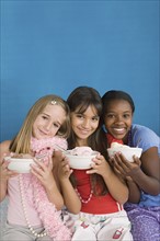 Portrait of three girls (10-11) holding desserts at slumber party. Photo : Rob Lewine
