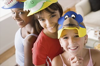 Portrait of three girls (10-11) wearing funny hats at slumber party. Photo: Rob Lewine