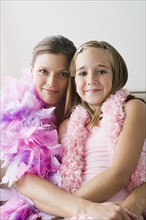 Portrait of mother and daughter (10-11) wearing feather boa at slumber party. Photo : Rob Lewine