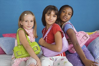 Portrait of three girls (10-11) wearing colorful purses. Photo: Rob Lewine