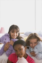 Portrait of three girls (10-11) with puppets in bed. Photo : Rob Lewine