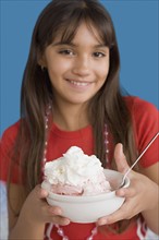 Portrait of smiling girl (10-11) holding dessert. Photo: Rob Lewine