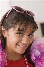 Portrait of smiling girl (10-11) wearing feather boa and sunglasses. Photo : Rob Lewine
