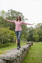 USA, New Jersey, Woman balancing on stone wall. Photo : Tetra Images