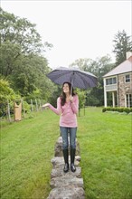 USA, New Jersey, Woman holding umbrella in backyard. Photo: Tetra Images