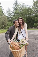 Portrait of couple on bike with basket. Photo: Tetra Images