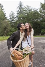Portrait of couple on bike with basket. Photo : Tetra Images