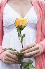 Close-up of woman holding yellow rose. Photo : Tetra Images