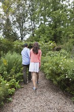 Rear view of couple walking through garden. Photo : Tetra Images