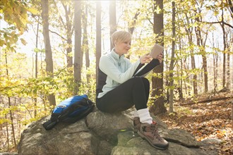 Female hiker using digital tablet in forest. Photo : Tetra Images