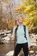 Female hiker standing by stream in forest. Photo : Tetra Images