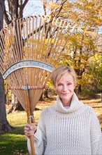Portrait of smiling woman with rake. Photo: Tetra Images