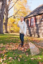 USA, New Jersey, Woman raking leaves in front of house. Photo: Tetra Images