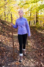 USA, New Jersey, Smiling woman hiking in Autumn forest. Photo : Tetra Images