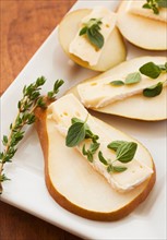 Studio shot of sliced pear with herbs.