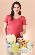Studio portrait of woman with shopping basket full of baby goods.