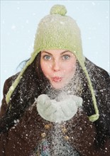 Studio portrait of woman blowing snow.