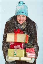 Studio portrait of woman in winter clothing carrying presents.