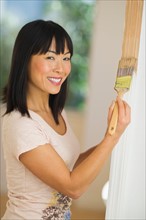 Smiling woman painting door frame.