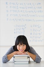 Portrait of smiling woman in front of board with equations.