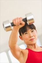 Mid adult woman exercising with dumbbells.