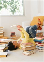 Woman reading among stacks of books.