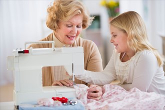 Grandmother with granddaughter (8-9) sewing together.
