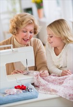 Grandmother with granddaughter (8-9) sewing together.