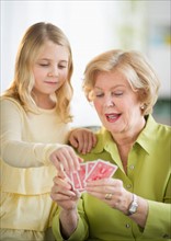 Grandmother with granddaughter (8-9) playing cards.