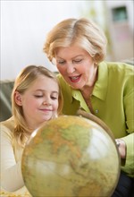 Grandmother with granddaughter (8-9) looking at globe.