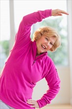 Portrait of smiling senior woman stretching.