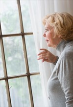 Portrait of senior woman looking through window.