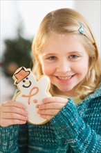 Girl (8--9) holding gingerbread cookie.