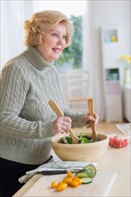 Senior woman preparing salad .