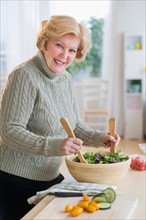 Senior woman preparing salad .