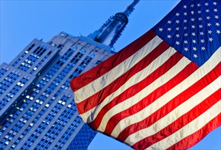 USA, New York State, New York City, American flag with Empire State Building in background.