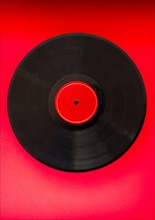 Vinyl record in on red background, studio shot.