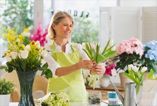 Senior female florist arranging bouquet.