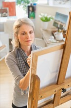 Portrait of senior woman painting on canvas.