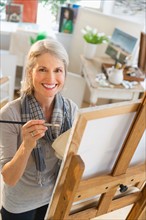 Portrait of senior woman painting on canvas.